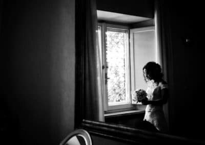 Sposa alla finestra che guarda il suo bouquet