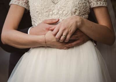 lo sposo abbraccia da dietro la sposa e le loro mani si intrecciano